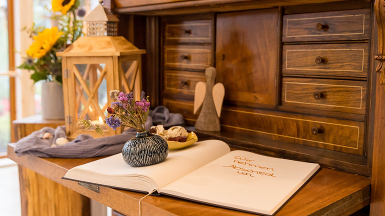 Ein Holzsekretär mit einem Buch, Engel und Blumenvase im Albertinen Hospiz Norderstedt