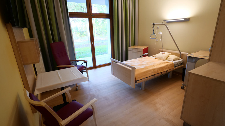 Blick in Gästezimmer mit Mobiliar und Blick durch Terrassenfenster - Albertinen Hospiz Norderstedt