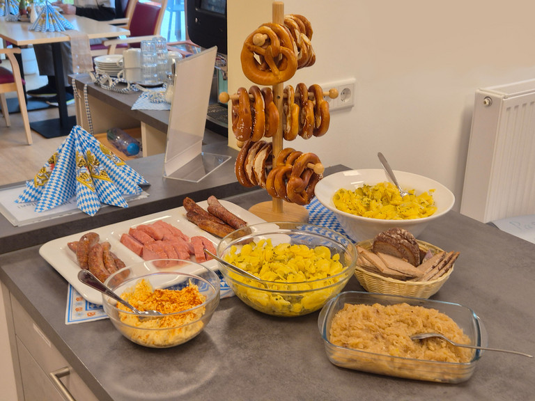 Oktoberfestlich dekoriertes Buffet mit Brezeln, Bratwurst, Leberkäse, Kartoffelsalat, Sauerkraut und Brot im Albertinen Hospiz Norderstedt.