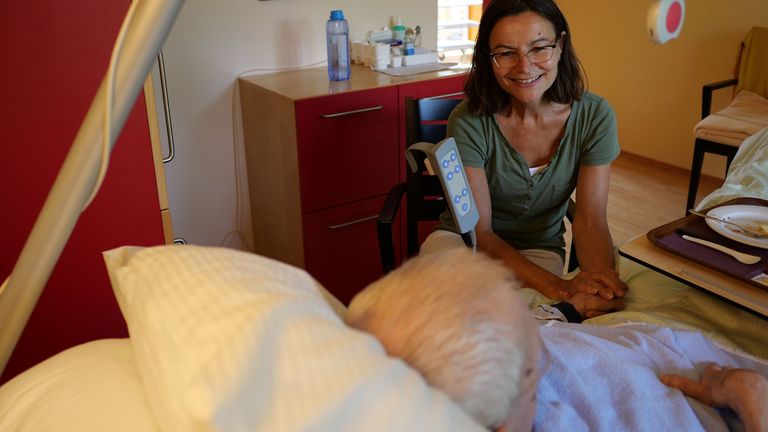 Eine ehrenamtliche Mitarbeiterin sitzt am Bett eines älteren Menschen im  Albertinen Hospiz Norderstedt, Seite Unterstützen Sie uns