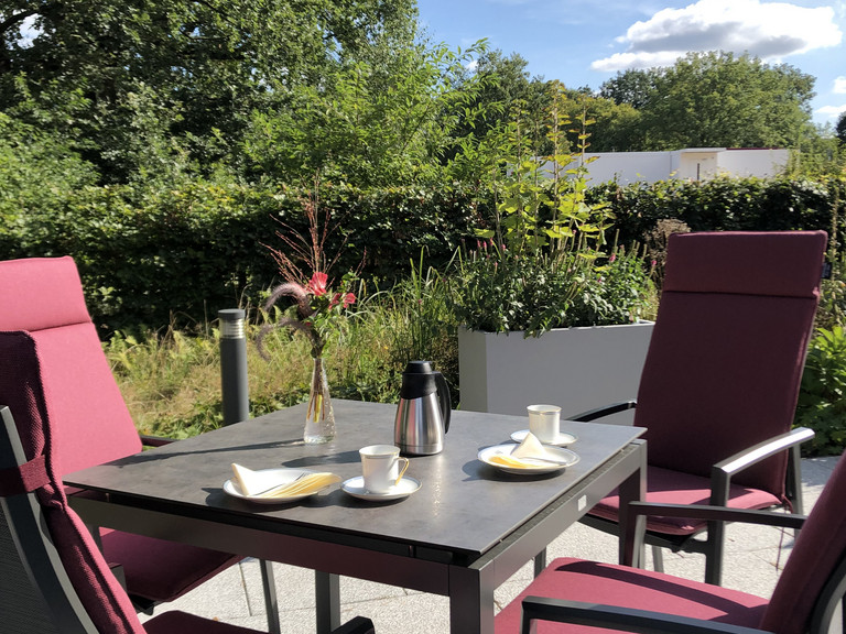 Blick auf einen gedeckten Tisch und Stühle auf der Terrasse im Albertinen Hospiz Norderstedt