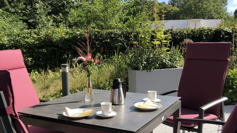 Blick auf einen gedeckten Tisch und Stühle auf der Terrasse im Albertinen Hospiz Norderstedt