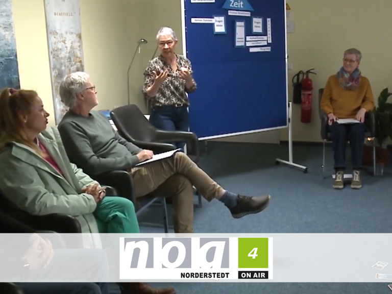 Kursleiterin Sabine Bornhöft steht an einer Pinnwand und spricht mit den im Kreis sitzenden Teilnehmenden beim Kurs für den ehrenamtlichen mobilen Hospizdienst im Albertinen Hospiz Norderstedt.