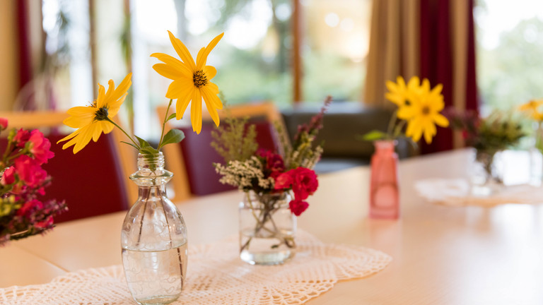 Blühende Blumen stehen in verschiedenen Vasen auf einem Tisch im Albertinen Hospiz Norderstedt